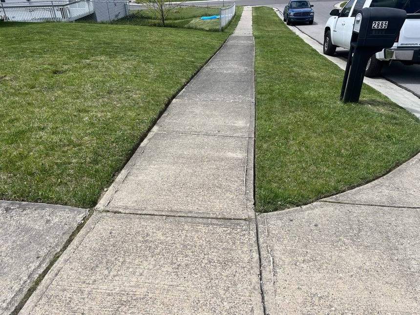 A freshly mown lawn with a razor-straight edge cut along the concrete walk and driveway of a Cincinnati house.